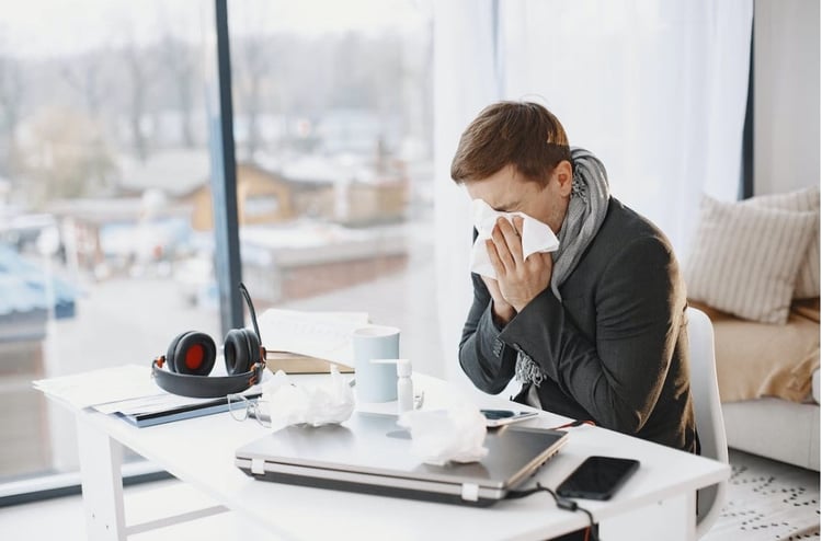 A-person-blowing-their-nose-and-feeling-unwell-due-to-the-effects-of-sick-building-syndrome