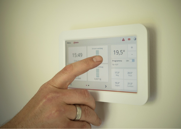  A person using a smart thermostat that is properly functioning and reliable due to annual checks, meaning employees can work in comfortable conditions.