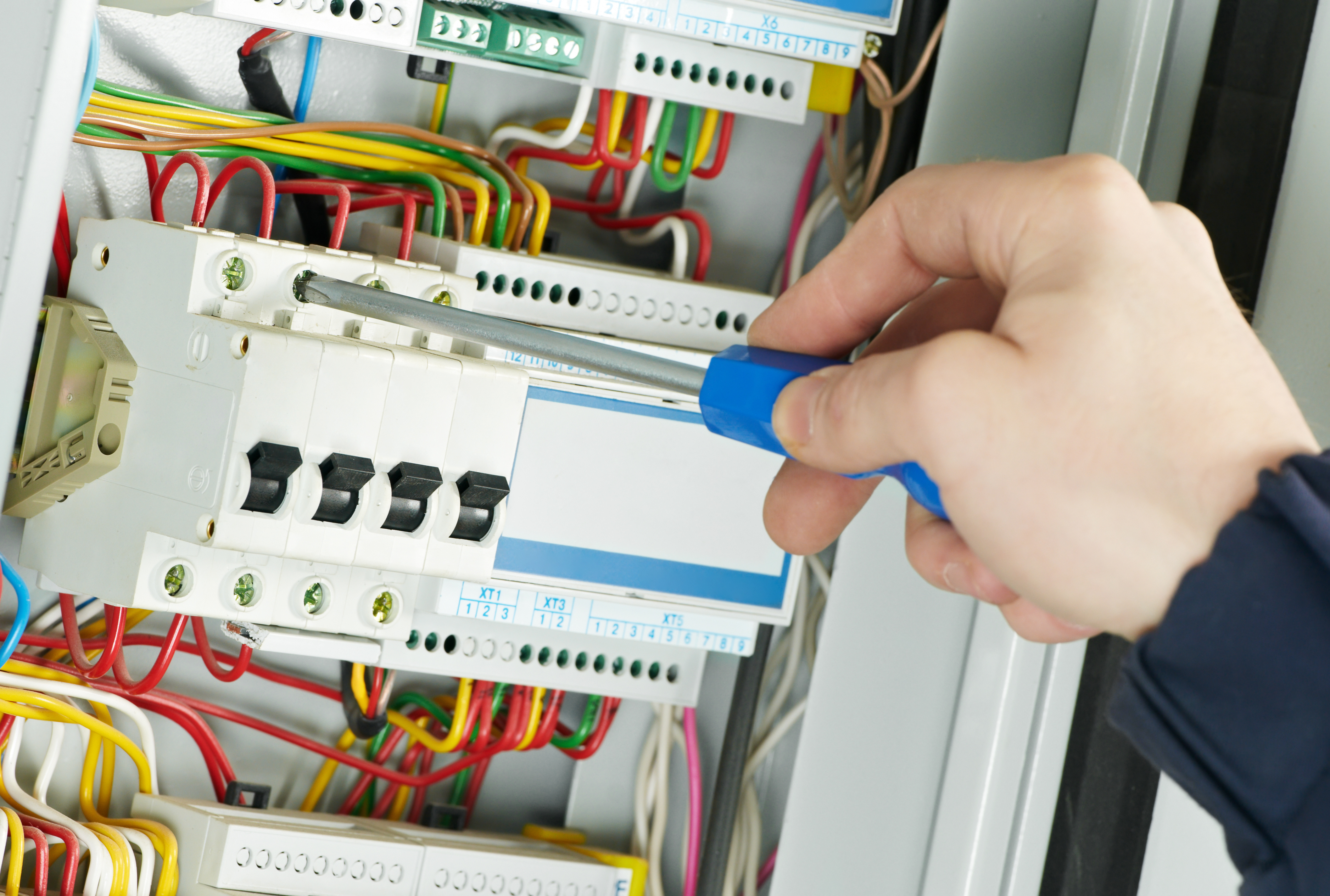electrician testing wires in a system to show that you should ensure your building's electrical system is safe with fixed wire testing